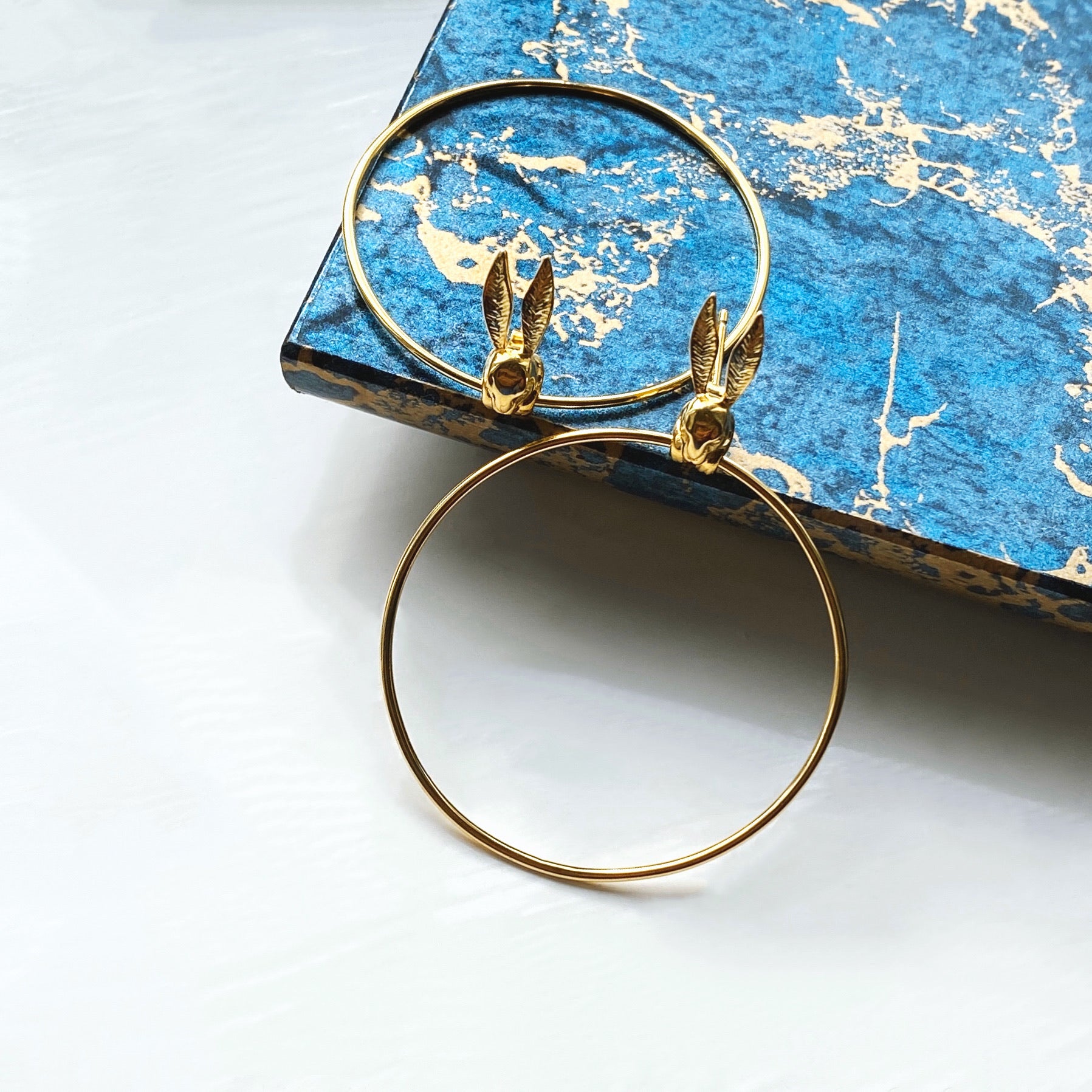 our bunny earrings on gold side perfectly on a blue and gold marble top. 
