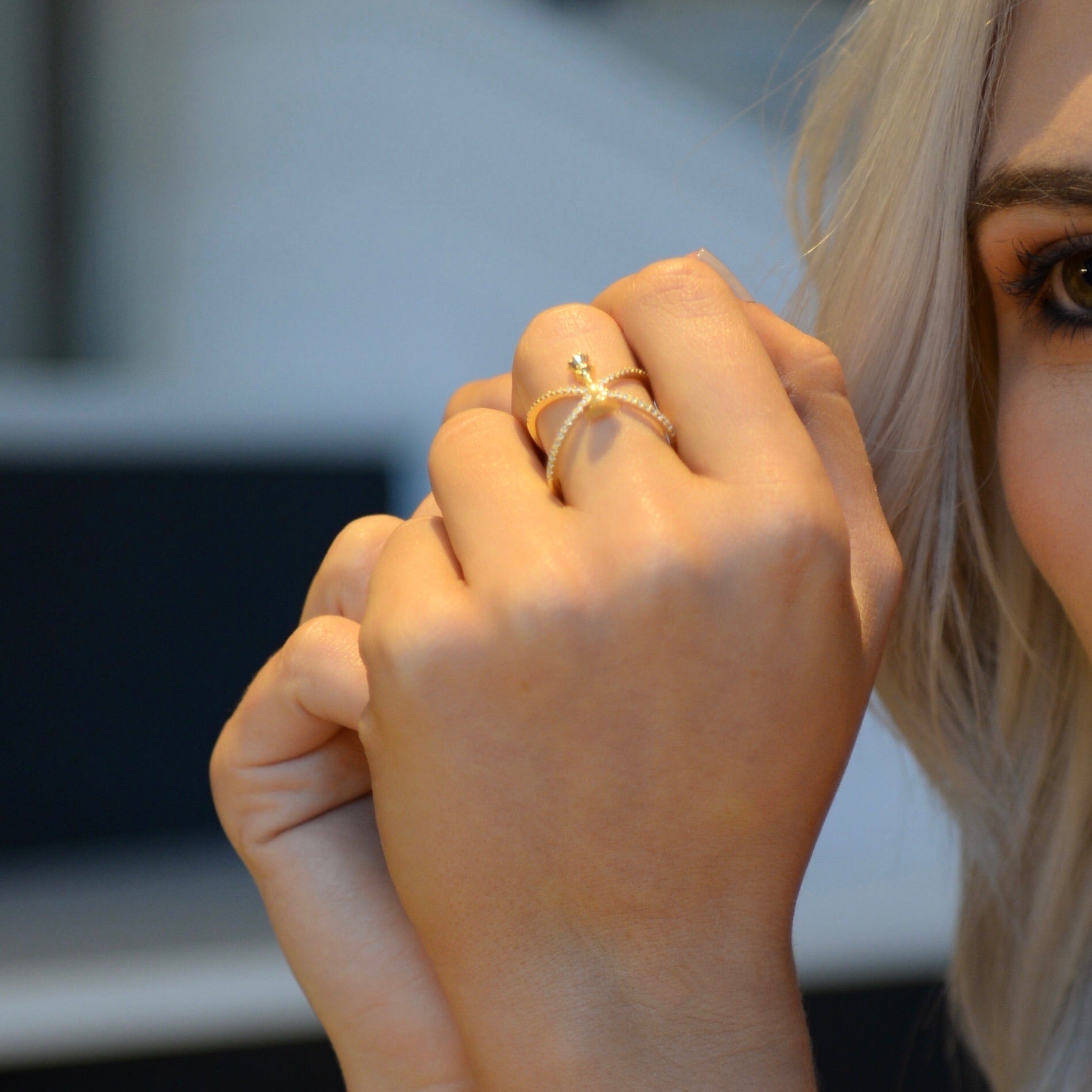 woman looks in to the distance with her hand interlocked, showing our queen statement ring in gold